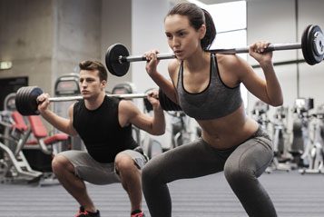 Two people doing a squat with a barbell